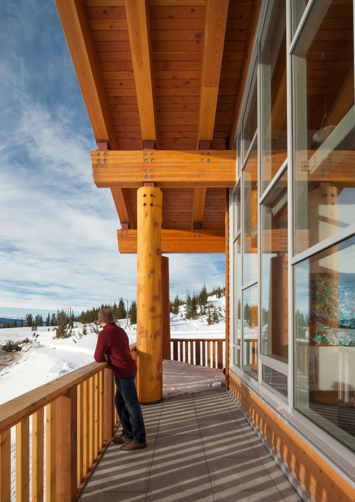 胶合木(胶合木)梁、木墙板和拱脚、实锯重型木材垂直杆柱、多维度木材扶手和栏杆都显示在温哥华岛山中心占据外部阳台的雪天阳光图像中