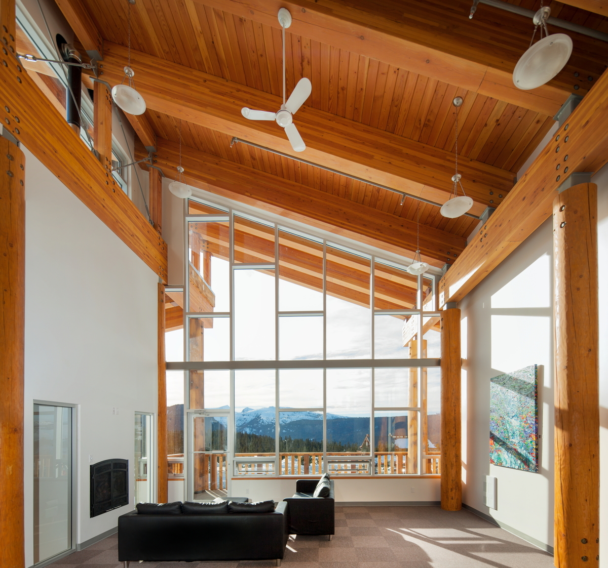 日光下的温哥华岛山中心中庭室内图像，显示胶合木(胶合木)梁，圆形实锯重木柱支撑舌形和槽形木板天花板