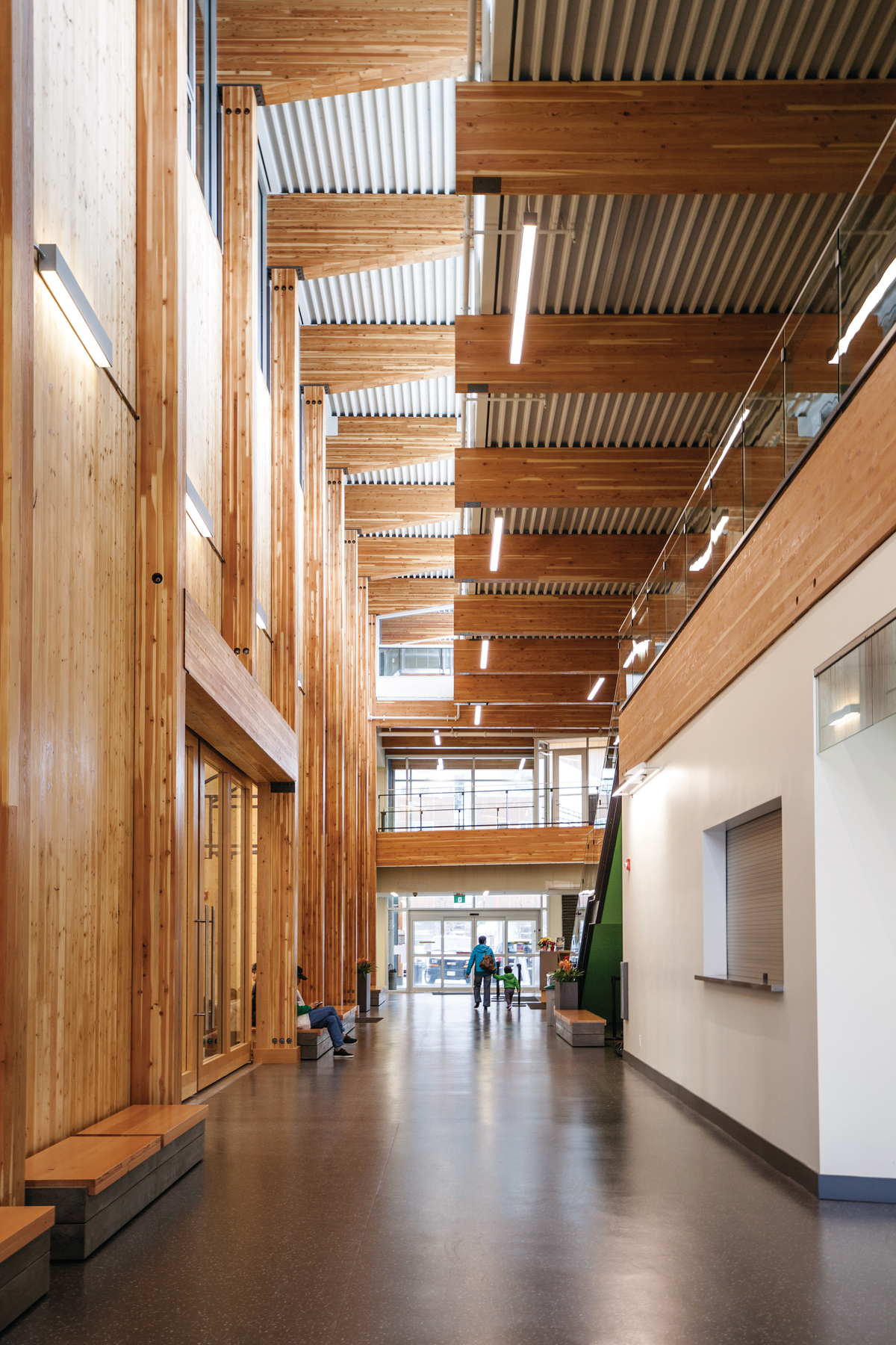 韦斯布鲁克社区中心多层低层中庭的室内白天一楼图像，显示交叉叠层木材(CLT)墙板，全跨度水平胶合木(胶合木)天花板梁，垂直柱，和广泛使用的木材装饰