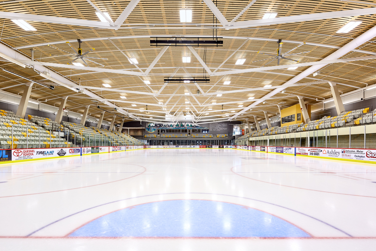 西弗雷泽中心低层溜冰场的内景，展示专业尺寸的溜冰场，可容纳1300人的座位，拱形木天花板和钢支撑桁架。