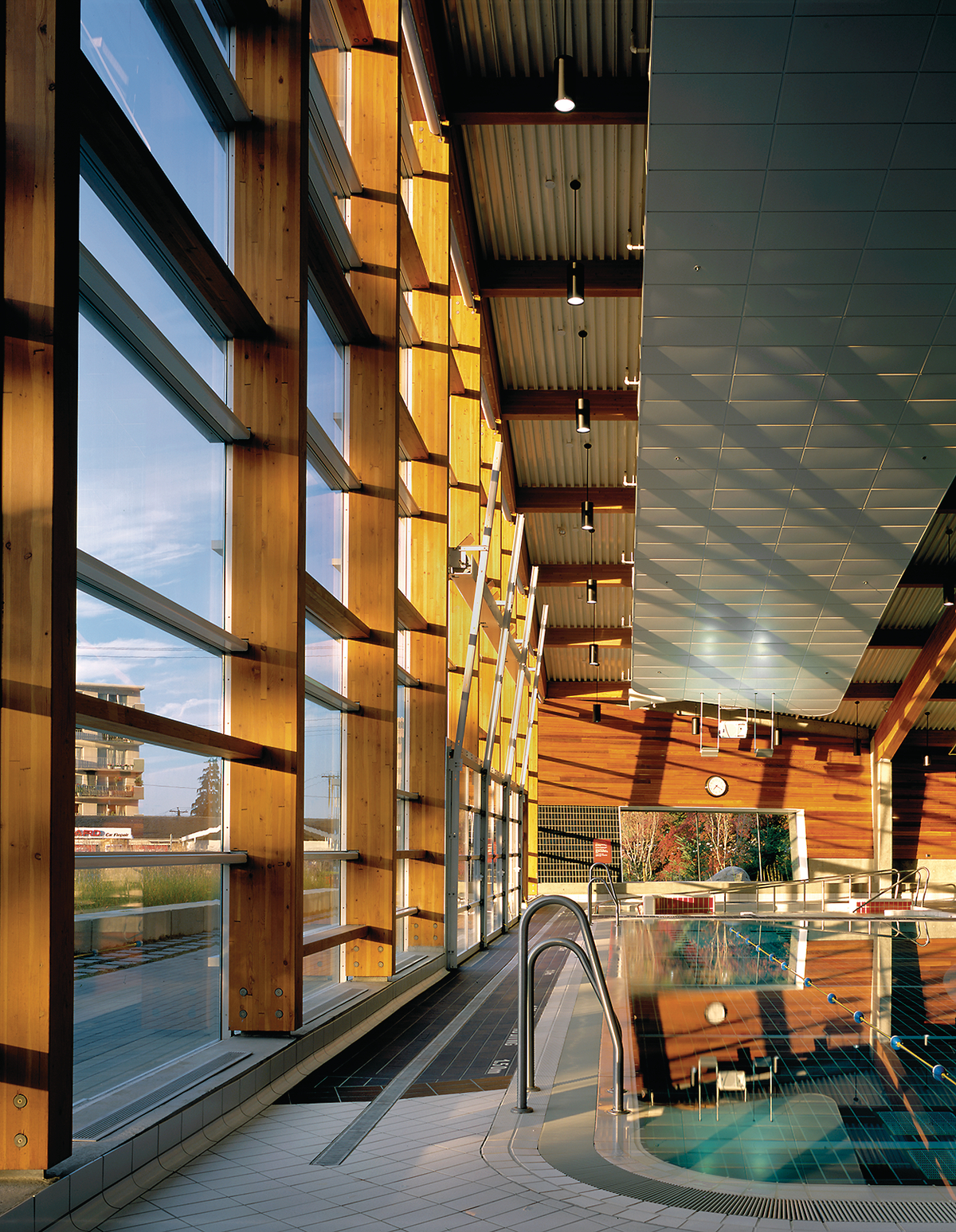西温哥华水上中心低层的室内日间景观，显示从地板到天花板的玻璃外墙板，垂直胶合木(胶合木)柱支撑胶合木(胶合木)屋顶梁，以及木板镶板
