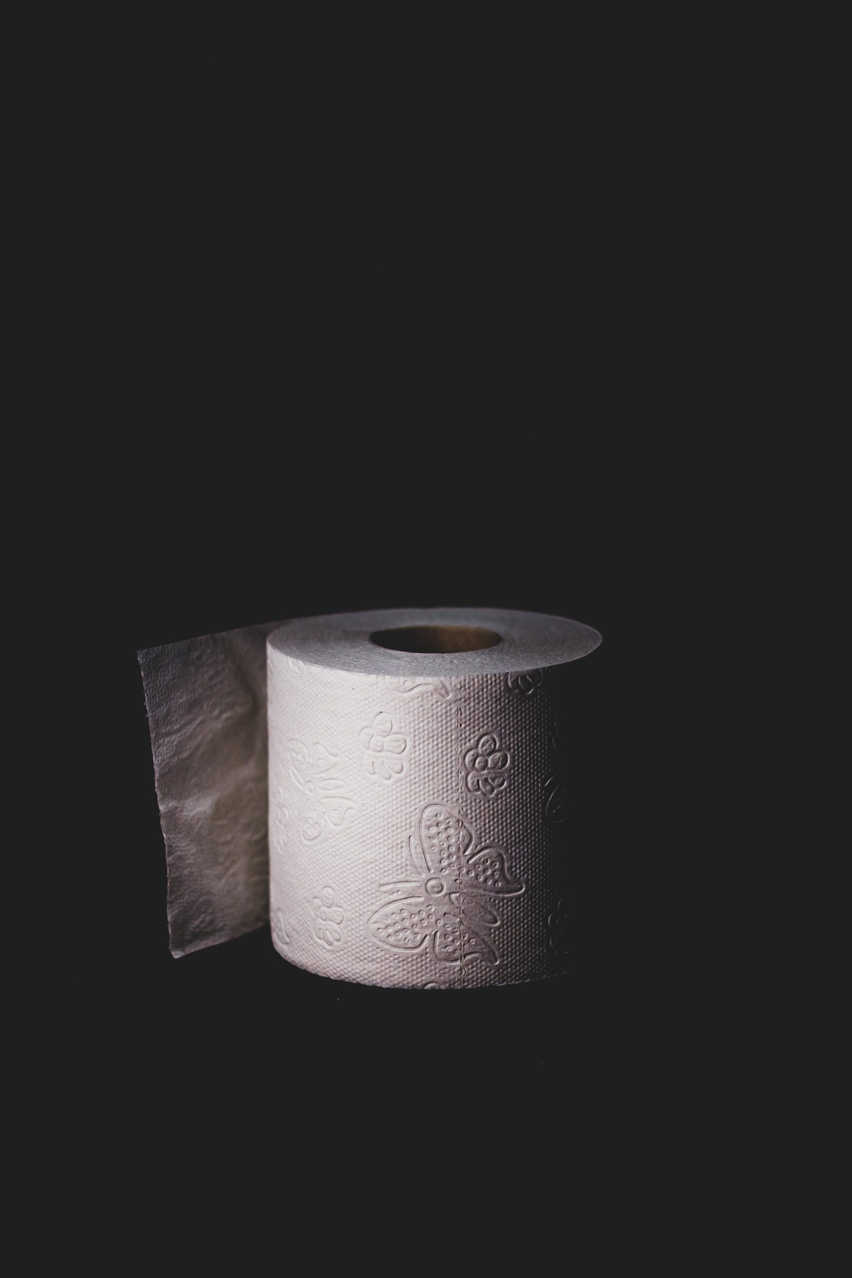 一卷厕纸在黑暗的背景与微妙的照明