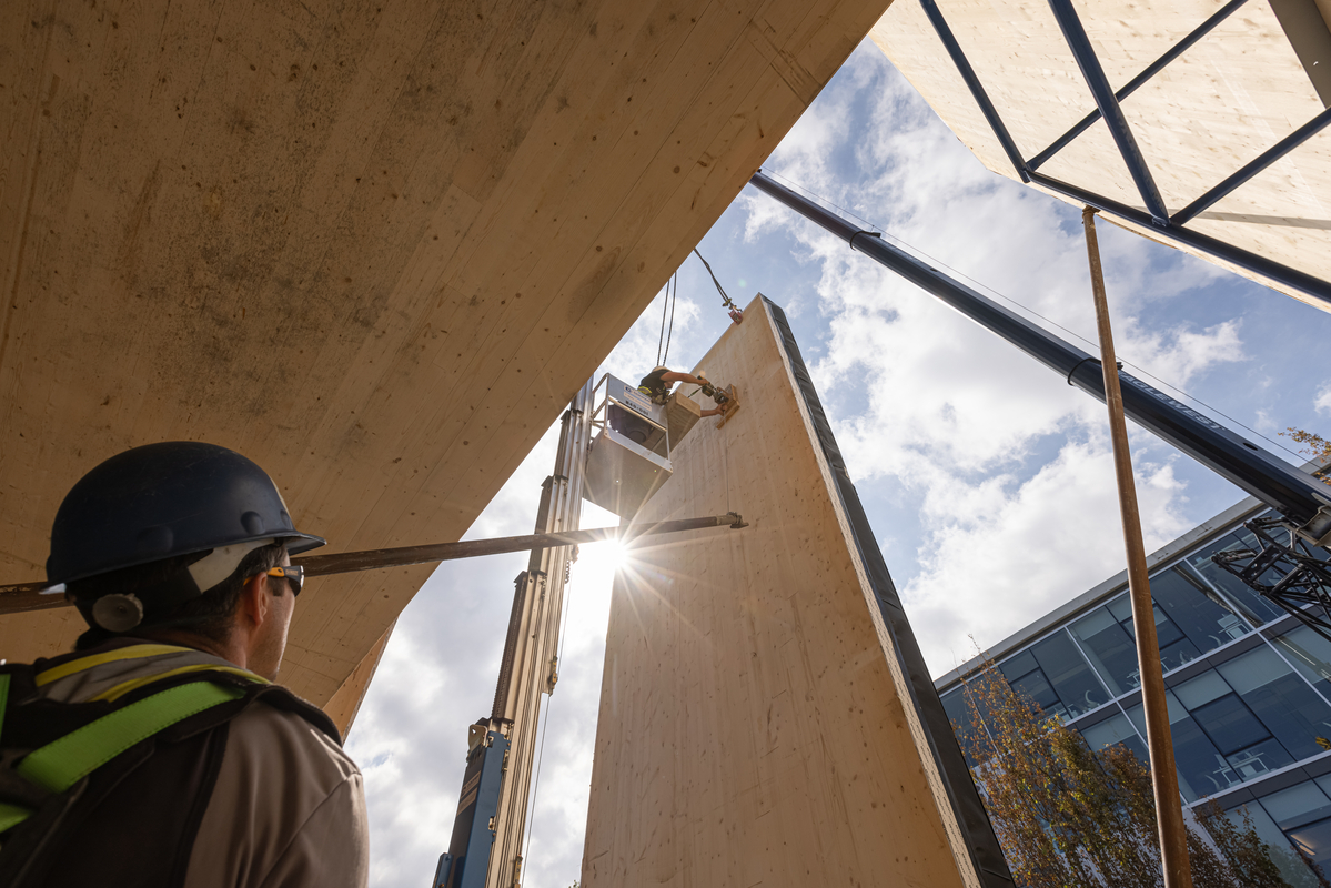建筑工人抬起头很大垂直挂在起重机此时面板,面板背后的太阳光照耀。
