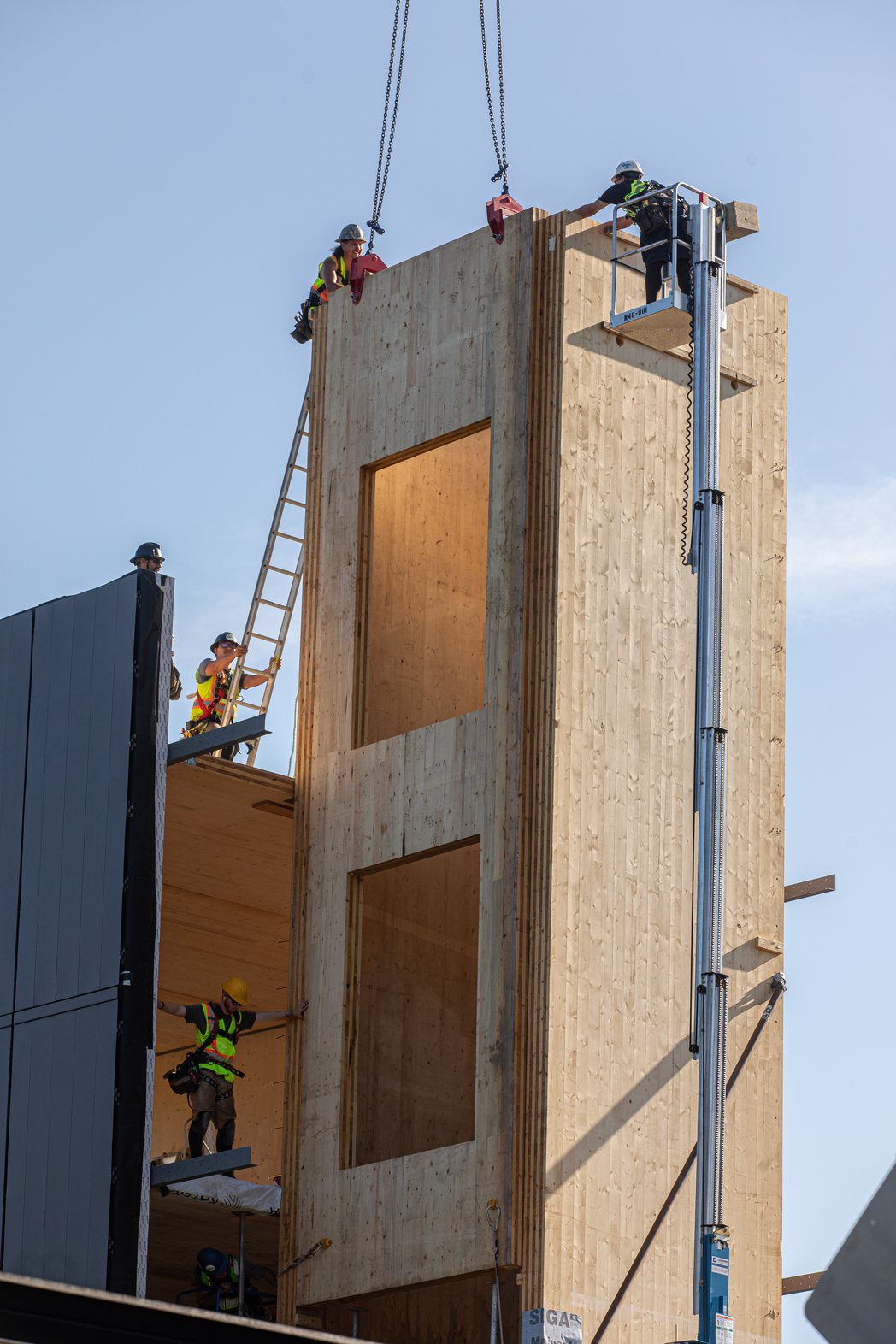 建筑工人将电梯井用的预制木板从起重机上吊下来。