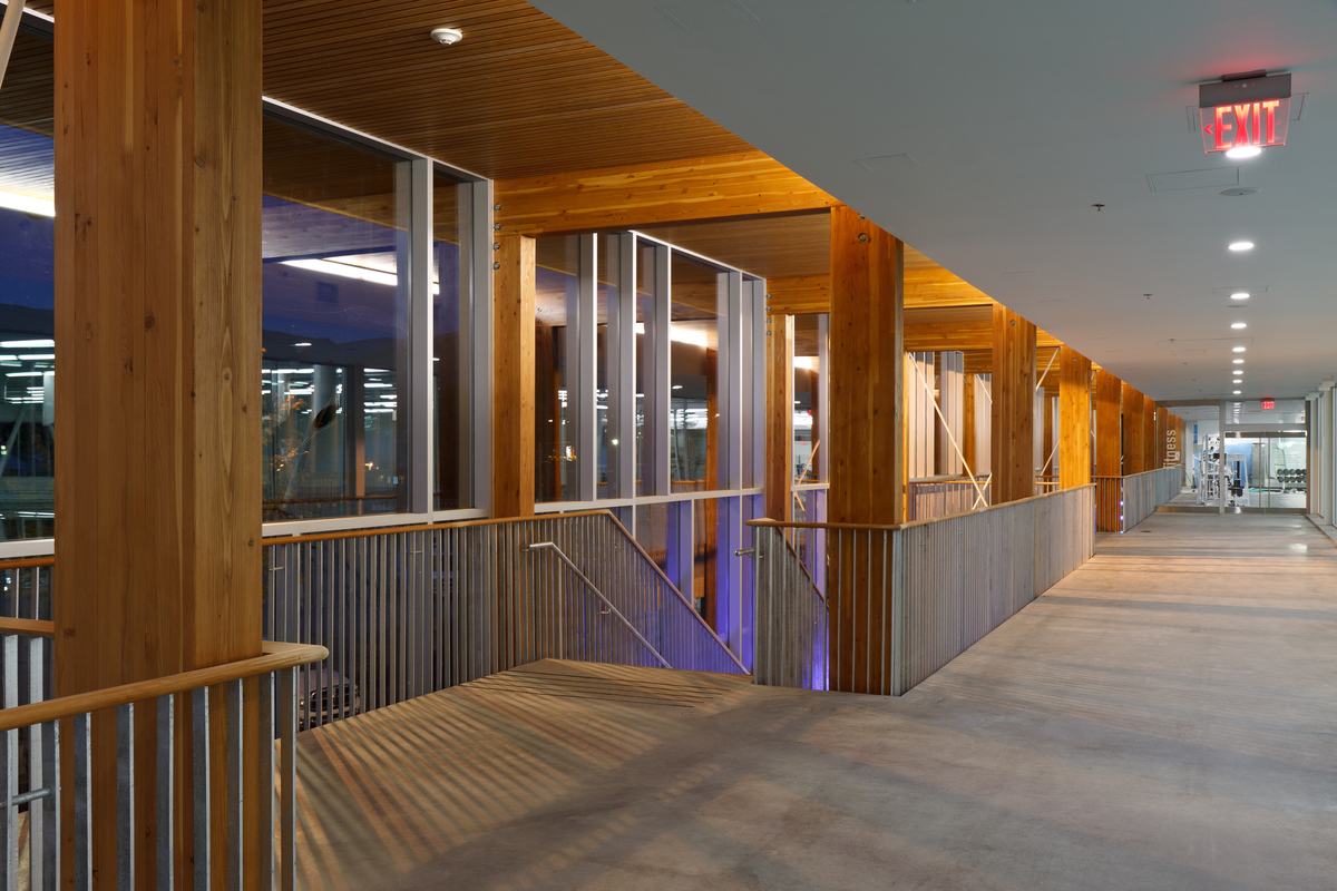 彭提顿社区中心顶层的内景，显示主楼梯井与胶合木(胶合木)柱和板条木材天花板上方，重量室的背景